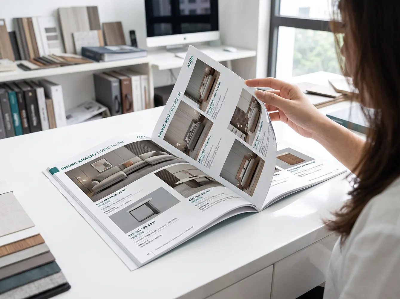Một người đang lật xem cuốn catalogue sản phẩm trên bàn, thể hiện bố cục rõ ràng, hình ảnh chất lượng và thông tin dễ đọc.